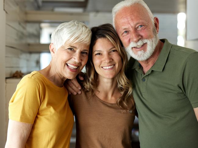 Happy adult daughter enjoying with her mature parents at home and looking at camera; Bank of Mum and Dad generic money