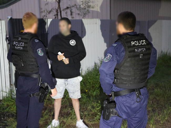 Police speak with a man during searches of bikies’ properties in the Hunter.