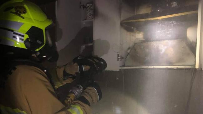 A Fire and Rescue NSW firefighter from the Forestville brigade puts out a fire in the rangehood in a home in Hurdis Ave, Frenchs Forest after a smoke alarm alerted the sleeping family. Picture: Fire and Rescue (Forestville)