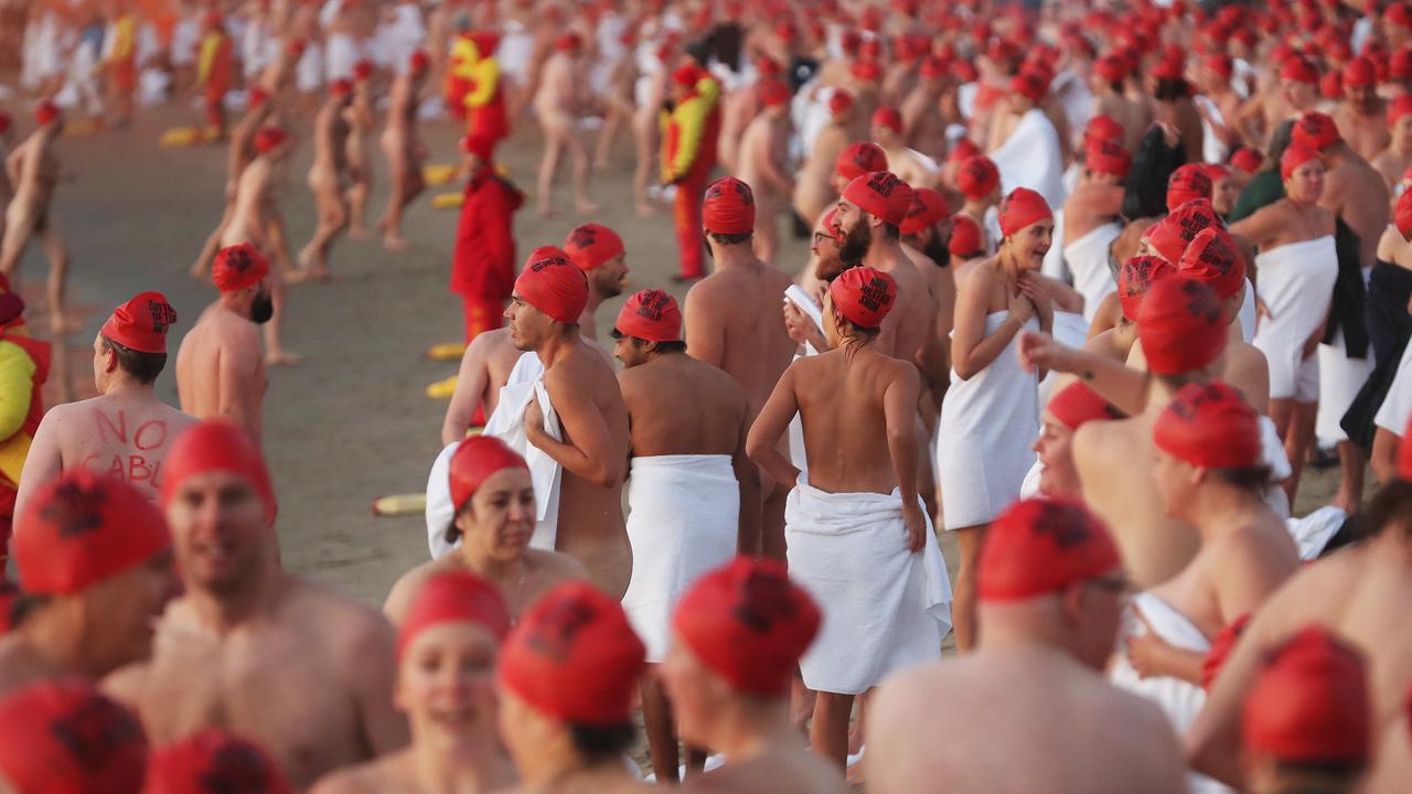 Hundreds of nudist people running into the sea naked