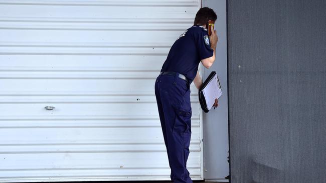 A police officer examines bullet holes on a garage door at the property: Shae Beplate.