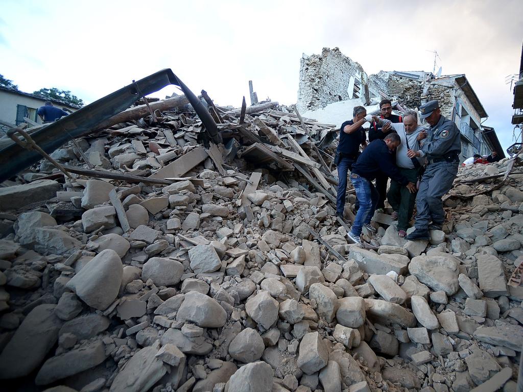 Residents and rescuers help a man among the rubble after a strong earthquake hit Amatrice on August 24, 2016. Picture: AFP