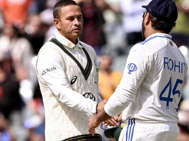 India's captain Rohit Sharma (R) shakes hands with Australia's Usman Khawaja (C) on the third day of the second cricket Test match between Australia and India at the Adelaide Oval in Adelaide on December 8, 2024. (Photo by William WEST / AFP) / -- IMAGE RESTRICTED TO EDITORIAL USE - STRICTLY NO COMMERCIAL USE --