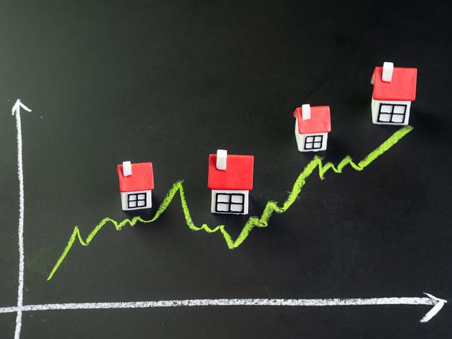 House, property or real estate market price go up or rising concept, small miniature house with green line graph going up on black chalkboard.