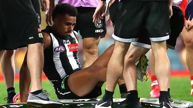 Collingwood’s Isaac Quaynor is taken off injured after suffering a deep gash up to 21cm long on his shin. Picture: Getty Images