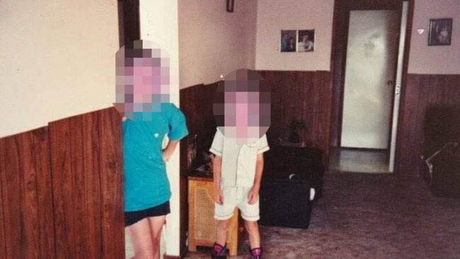 A pale white apparition appears in front of a door in a family photo.