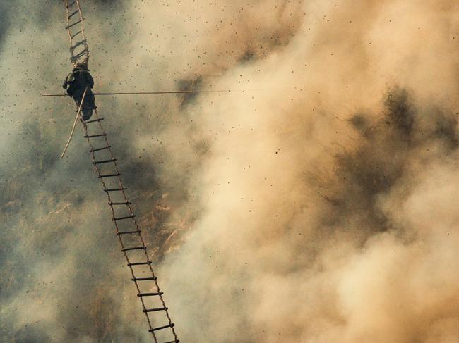 The work of Nepalese honey hunters is perilous: nests, as large as the men that hunt them, are high on sheer cliff walls and guarded by thousands of irascible bees. Hunters descend rope ladders, armed with tool-tipped poles, and joust against the swarm to sever the honey from the hive. Picture: Eric Seidner