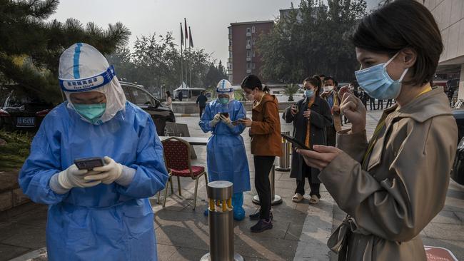 An epidemic control worker registers a woman for a nucleic acid test to detect Covid-19 as journalists, staff, and officials line up for test outside a closed loop hotel, for the 20th National Congress of the Communist Party of China. Picture: Getty Images