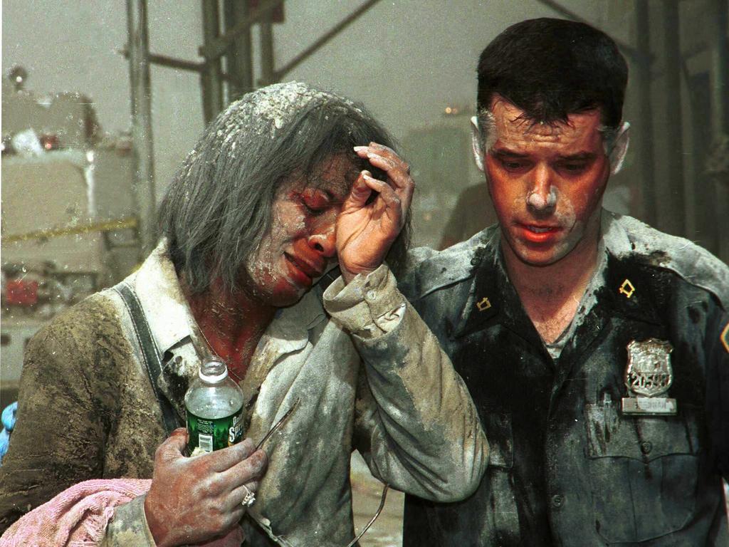 Police officer Michael Brennan helps a woman named Beverly to safety. She was covered in dust after the first tower went down. Picture: Joey Newfield/NY Post