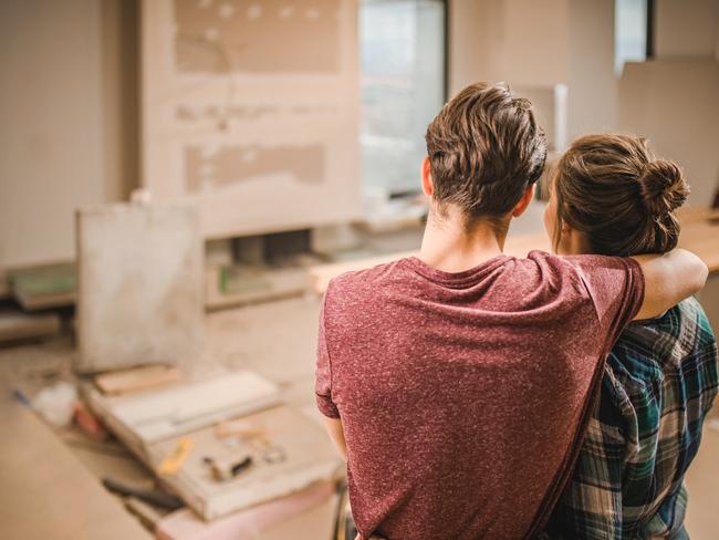 Rear view of loving couple standing embraced in their apartment that is renovating.