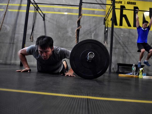 Gym enthusiasts exercise whilst maintaining distance from each other at CrossFit Arena Bangkok, during their first week of reopening following closure of physical wellness centers after authorities lifted some measures of restrictions to halt the spread of the COVID-19 coronavirus in Bangkok on May 20, 2020. (Photo by Lillian SUWANRUMPHA / AFP)