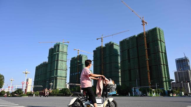 A woman rides a scooter past the construction site of an Evergrande housing complex in Zhumadian, central China’s Henan province. Picture: AFP