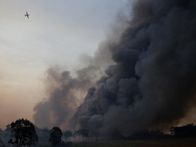 A spotter plane flies over the out of control fire at Avery's lane, near Stanford Merthyr, west of Newcastle, on Tuesday. Picture: AAP/Darren Pateman