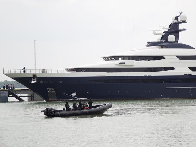 FILE - In this Aug. 7, 2018, file photo, Malaysia's marine police on their security boat watch luxury yacht Equanimity, allegedly bought with money stolen from the multibillion-dollar looting of a state investment fund, arriving at Port Klang in Klang, Malaysia. Malaysia's government launched a one-month auction for the luxury yacht bought with money stolen from the multibillion-dollar looting of a state investment fund. The sale that began Monday, Oct. 29, 2018, came nearly three months after Indonesia returned the $250 million yacht after seizing it off Bali in February in cooperation with the U.S. FBI. (AP Photo/Yam G-Jun, File)