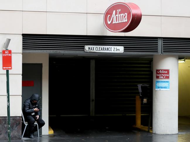 Security guard on his phone outside the Adina Apartment Hotel Sydney Town Hall. Picture: Jonathan Ng