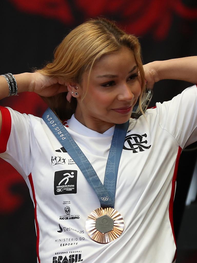 Flavia Saraiva fixes her medal after returning to Brazil. Photo by Wagner Meier/Getty Images