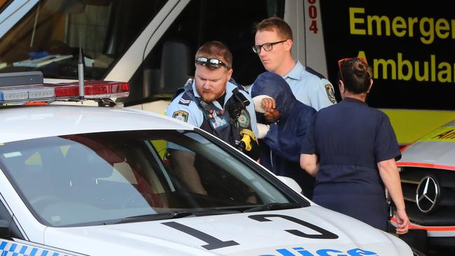 Mr Hossain with his head covered, leaves Fairfield Hospital with police on Sunday afternoon. Picture: Damian Shaw