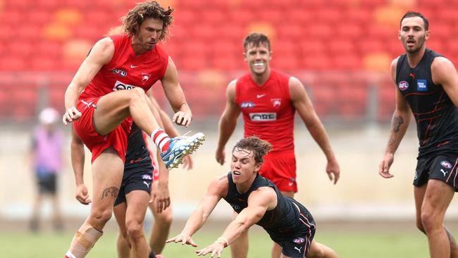 New Swans ruckman Tom Hickey gets a kick away under pressure.