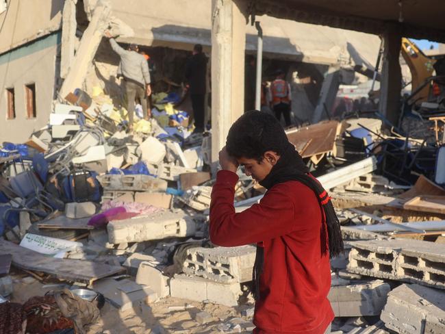 A boy walks on rubble as rescuers search for casualties following an Israeli strike on the municipality building in Deir el-Balah in the central Gaza Strip on december 14, 2024, as the war continues between Israel and the Palestinian Hamas group. Gaza's civil defence said Israeli strikes on the territory killed 17 people on December 14, ten at the Deir el-Balah town hall including mayor Deiab al-Jaro, and seven at the Al-Majida Wasila UN school housing displaced people west of Gaza City. (Photo by Eyad BABA / AFP)