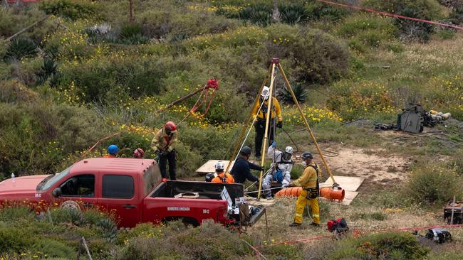 A rescue worker descends into a waterhole where human remains were found near La Bocana Beach, Santo Tomas delegation, in Ensenada, Baja California State, Mexico. Picture: Guillermo Arias / AFP