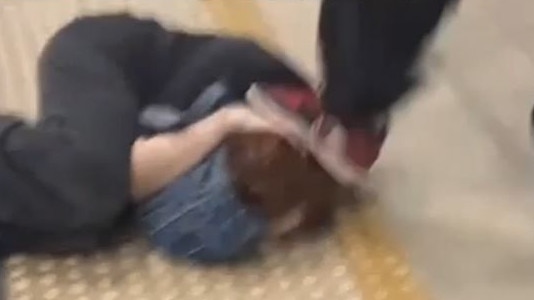 Shocking footage shows a young woman being repeatedly kicked while she cowers on a train platform at Town Hall.