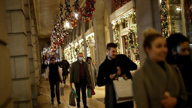 Britain's Chancellor of the Duchy of Lancaster Michael Gove (C) wearing a face mask or covering due to the COVID-19 pandemic, carries bags as he walks with pedestrians past the Ritz in London on December 19. Picture: AFP