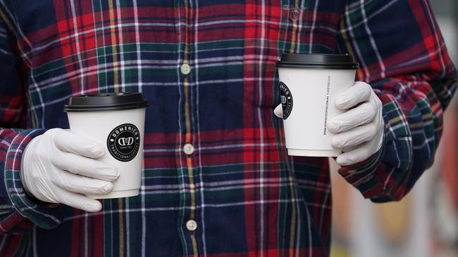 A member of the public is seen wearing gloves while leaving a cafe in Brunswick on Tuesday morning. Picture: AAP Image/Stefan Postles