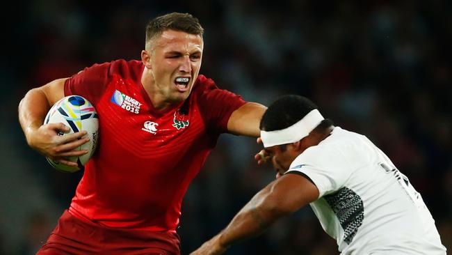 Sam Burgess of England hands off Tuapati Talemaitoga of Fiji.