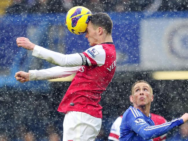 Arsenal's Belgian defender Thomas Vermaelen (L) heads the ball as Chelsea's Spanish striker Fernando Torres (R) watches.