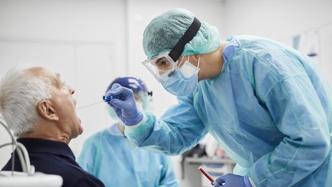 Doctor taking throat swab test from male patient. Medical worker is in protective workwear. They are at hospital during epidemic. Picture: Getty Images.