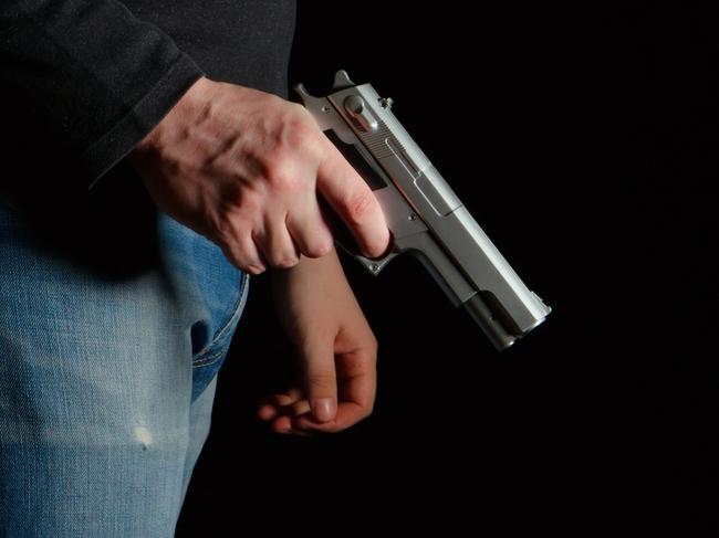 GENERIC PICTURE: Man with a gun in a dark room, man holding gun