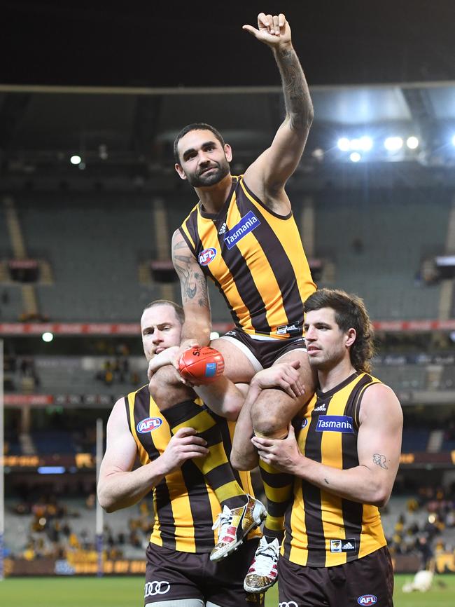 Empty stands at the MCG — and full lounge rooms across Australia — on Saturday night when Hawthorn great Shaun Burgoyne, chaired off here by Jarryd Roughead and Ben Stratton, played his 350th AFL game. Picture: AAP Image/Julian Smith