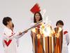 (FILES) In this file photo taken on March 25, 2021, Japanese torchbearer Azusa Iwashimizu (L), a member of Japan women's national football team, lights the Olympic torch on day one of the torch relay in Naraha, Fukushima Prefecture. - From a historic virus postponement and summer heat fears to unprecedented restrictions on fans, the path to staging the Tokyo Olympics, which begin in nearly one month on July 23, 2021, has been far from smooth. (Photo by KIM KYUNG-HOON / POOL / AFP)