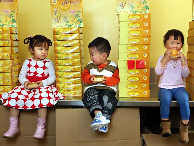 Sophia Tran, 3, Alex Lam, 2, and Fiona Kuch, 2, enjoying an early tasting of moon cakes that have been baked for the Cabramatta Moon Festival at the An Phat Bakery.