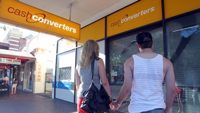 Young couple standing in front of closed Cash Converters store on Gouger Street, Adelaide.