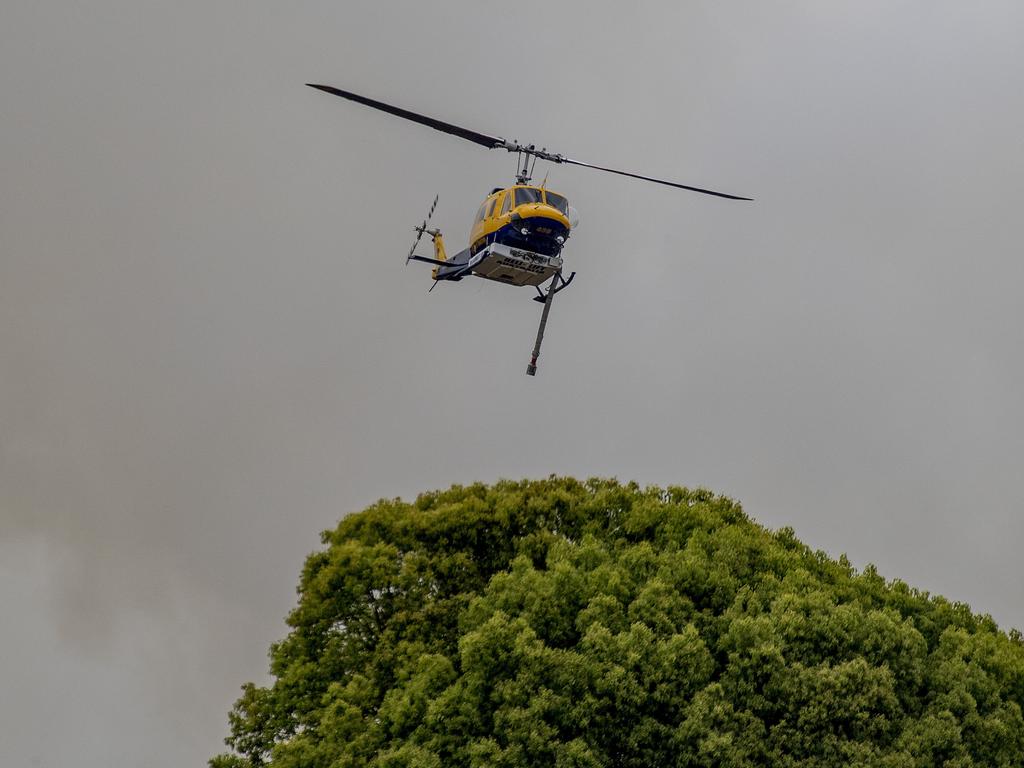 Smoke haze covers the Gold Coast Skyline from a grass fire at Carrara. A firefighting helicopter collects water from Judy Turners property in Carrara . Picture: Jerad Williams