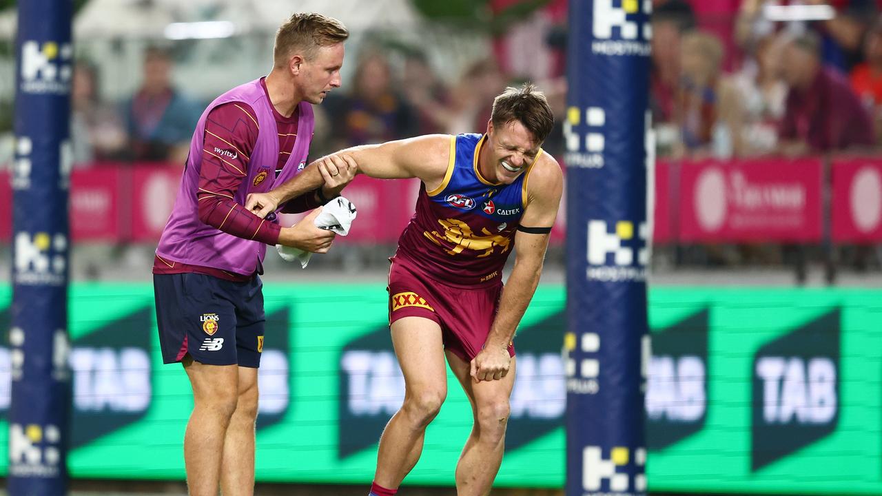 Linc McCarthy (right) is helped by a Lions trainer after injuring his knee. Picture: Chris Hyde/AFL Photos/via Getty Images