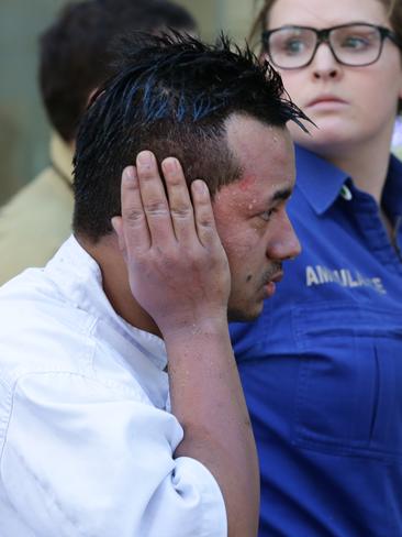 A employee with burns leaves the cafe with emergency services staff.