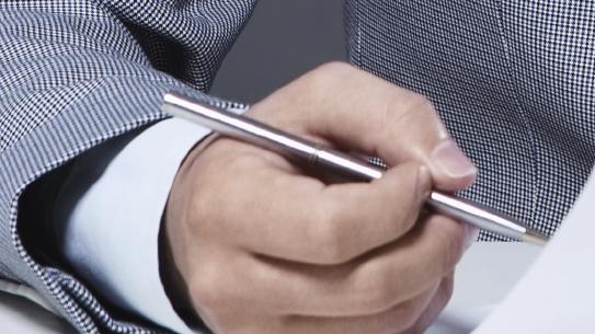 A young businessman signs a contract with a blindfold