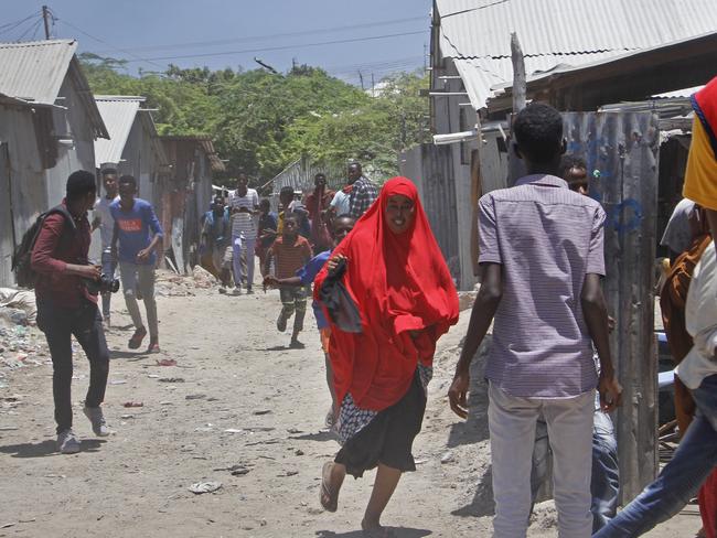 Somali civilians and medical workers run for cover from gunfire during ongoing fighting between government soldiers and gunmen after a suicide car bomb attack on a government building in the capital Mogadishu, Somalia Saturday, March 23, 2019. Al-Shabab gunmen stormed into the government building following a suicide car bombing at the gates on Saturday, a police officer said, in the latest attack by Islamic extremist fighters in the Horn of Africa nation. (AP Photo/Farah Abdi Warsameh)