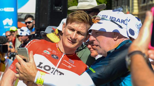 German rider Andre Greipel (L) from Lotto Soudal looks at a photo by a spectator prior to the start of the first day of the Tour Down Under cycling race in Port Adelaide on January 16, 2018. / AFP PHOTO / BRENTON EDWARDS / --IMAGE RESTRICTED TO EDITORIAL USE - STRICTLY NO COMMERCIAL USE--