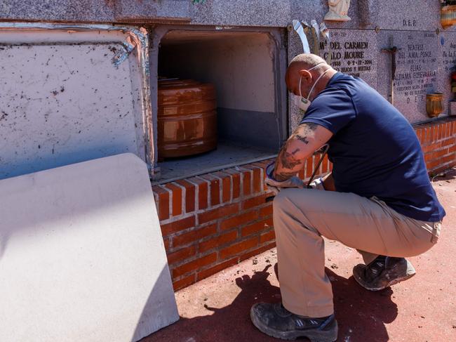 A mortuary employee wearing a face mask places the coffin of a COVID-19 victim into a niche during a burial at the Fuencarral cemetery in Madrid, Spain. Picture: AFP