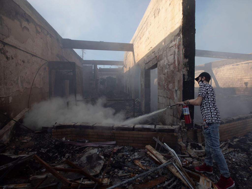 A man uses a fire extinguisher to try to put out the remainder of a fire after a riot broke out in Minneapolis, Minnesota. Picture: Chris Juhn/ZUMA Wire/Alamy Live News