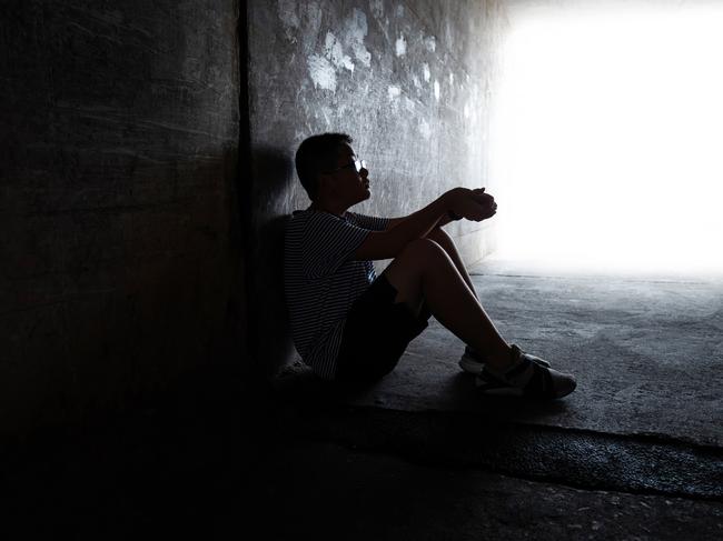 A boy sitting in the dark tunnel.