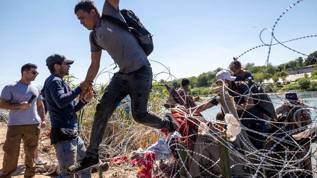 EAGLE PASS, TEXAS - SEPTEMBER 28: Immigrants cross over razor wire after crossing from Mexico into the United States on September 28, 2023 in Eagle Pass, Texas. A surge of asylum seeking migrants crossing the U.S. southern border has put pressure on U.S. immigration authorities, reaching record levels in recent weeks.   John Moore/Getty Images/AFP (Photo by JOHN MOORE / GETTY IMAGES NORTH AMERICA / Getty Images via AFP)