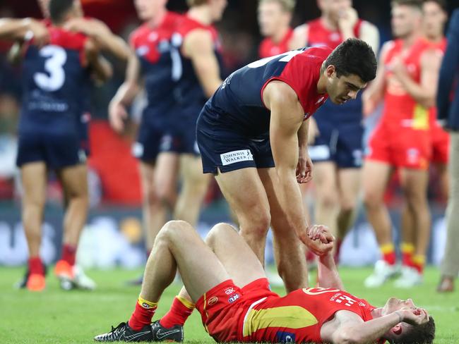 Christian Petracca of the Demons helps Pearce Hanley from the field after the round eight AFL match between the Gold Coast Suns and the Melbourne Demons at Metricon Stadium on May 11, 2019 in Gold Coast, Australia. (Photo by Chris Hyde/Getty Images)