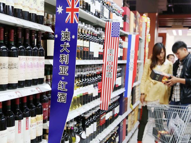 --FILE--Chinese customers shop for wine imported from Australia, the United States or France at a supermarket in Xuchang city, central China's Henan province, 17 October 2013.  Chinese buyers have developed a taste for more than just Australian stock of residential property and farmland, there's a renewed thirst for Australian wine in Asia, helping to drive the first annual increase in the value of exports in eight years. After years of suffering through a sustained austerity campaign from central government officials in Beijing, which put a dampener on banqueting and sapped demand for anything tinged with luxury, including wine, spirits and expensive watches, the middle class and richer Chinese are once again in the mood to buy. And increasingly they are reaching for a bottle of premium Australian wine. The weaker Australian dollar is also playing its part, while free-trade agreements in Asia are delivering immediate sales to Australian winemakers. According to Wine Australia, the value of Australian wine exports in the 12 months to June 30 rose 5 per cent to $1.89 billion, the first time the value of exports has increased on a financial year basis since 2006-07.