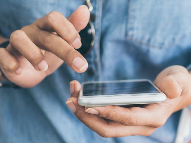 WOMAN MOBILE PHONE SUPERMARKET STOCK -  Woman wearing blue jeans shirt and sunglasses using mobile phone to compare price and holding orange shopping basket in mini mart background. Picture: Istock