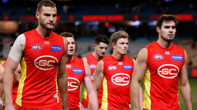 Suns players leave the field after the loss to Melbourne.