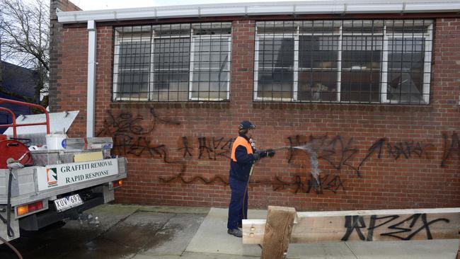 Steve Peters, from the council’s graffiti removal rapid response team, removes tags from a Nunawading building in 2012.